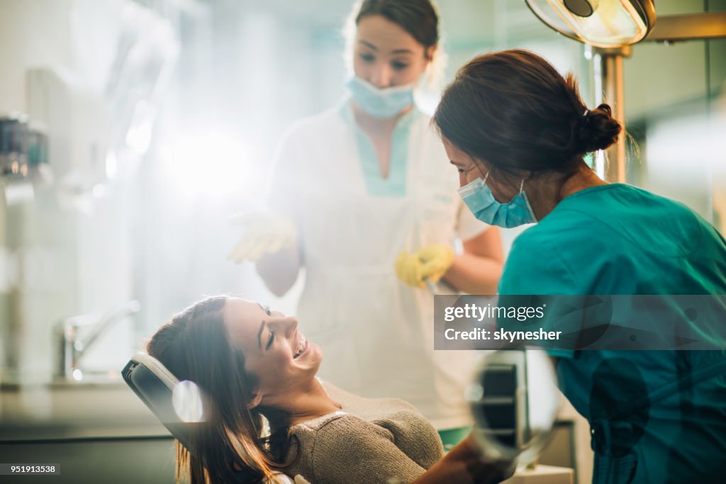 Young happy woman talking to a dentist before dental procedure.