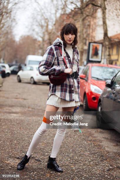 Polish model Karo Laczkowska wears a purple plaid Superdry flannel top, white knee-high socks, and black shoes during Milan Fashion Week Fall/Winter...