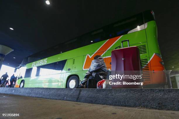 Traveler sits with her luggage beside a FlixBus passenger bus at Munich central bus station in Munich, Germany, on Friday, April 27, 2018. Since...