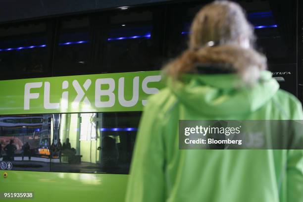 An employee stands beside a FlixBus passenger bus at Munich central bus station in Munich, Germany, on Friday, April 27, 2018. Since introducing a...