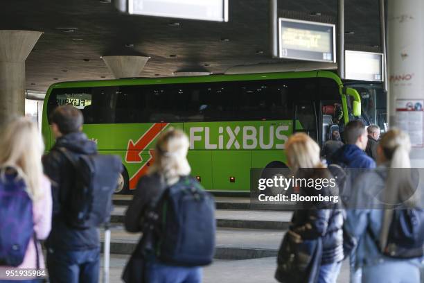 Travelers stand with their luggage as a FlixBus passenger bus sits parked at Munich central bus station in Munich, Germany, on Friday, April 27,...