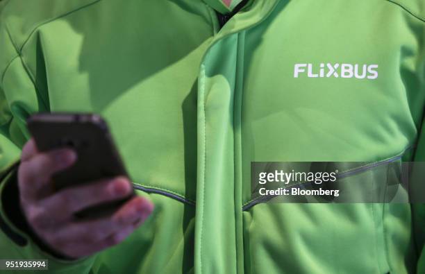 The FlixBus logo sits on an employee's jacket as they use a smartphone at Munich central bus station in Munich, Germany, on Friday, April 27, 2018....