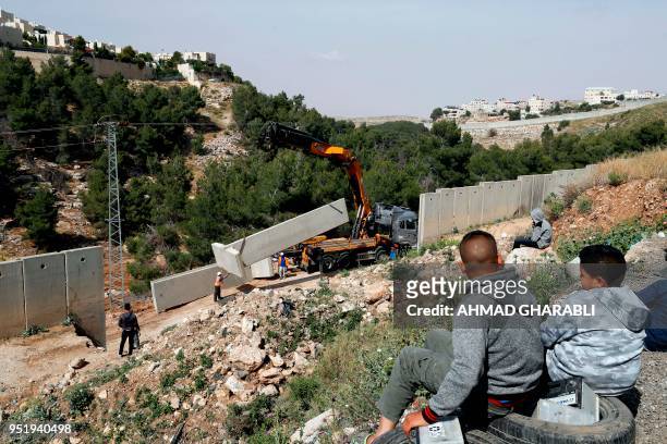 Picture taken on April 27, 2018 shows Palestinians from the Shuafat refugee camp in east Jerusalem watching as Israeli forces replace the collapsed...