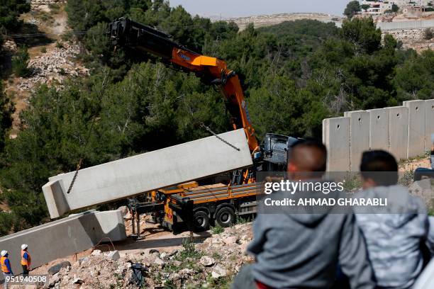 Picture taken on April 27, 2018 shows Palestinians from the Shuafat refugee camp in east Jerusalem watching as Israeli forces replace the collapsed...