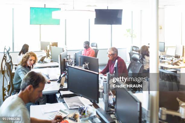 uomini d'affari che lavorano sui computer alla scrivania - uomini di età media foto e immagini stock