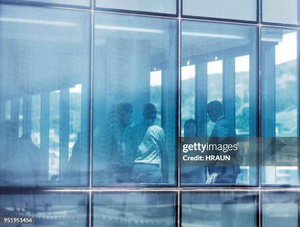 colleagues in meeting seen through glass at office - photographed through window stock pictures, royalty-free photos & images