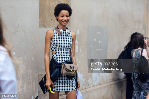 Model Lineisy Montero wears a black and white sleeveless gingham dress, a J.W. Anderson bag, and Beats headphones on July 03, 2017 in Paris, France.