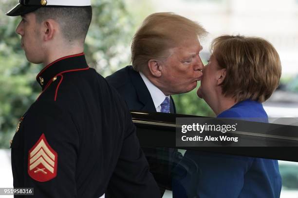 President Donald Trump kisses German Chancellor Angela Merkel during her arrival outside the West Wing of the White House April 27, 2018 in...