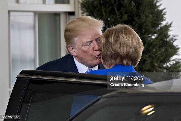 President Donald Trump kisses Angela Merkel, Germany's chancellor, right, while arriving to the West Wing of the White House in Washington, D.C.,...