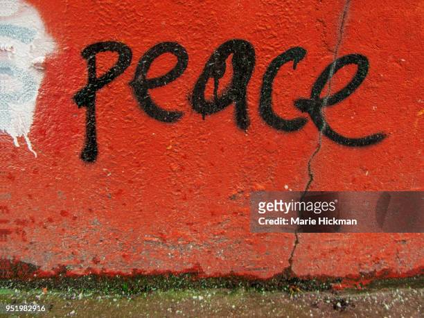 word peace hand written on an orange wall. - marie hickman stock-fotos und bilder