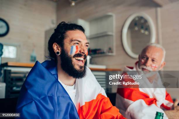men supporting french and uk national soccer teams watching game on tv - france supporter stock pictures, royalty-free photos & images