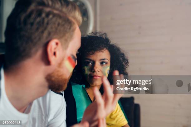 couple watching soccer game on tv and talking - german culture stock pictures, royalty-free photos & images