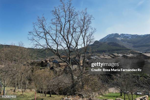 view of valverde de los arroyos, a village that conserves their tradicional architecture based on the use of the slate - rock, with  snowcapped mountain on background and clear sky. guadalajara, castilla la mancha, spain. - slate rock stock-fotos und bilder