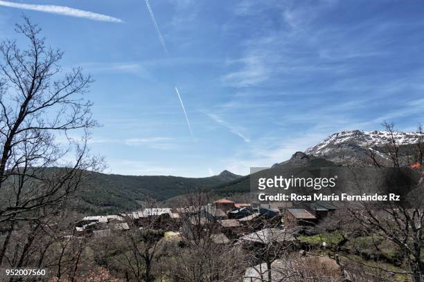 view of valverde de los arroyos, a village that conserves their tradicional architecture based on the use of the slate-rock, with  snowcapped mountain on background and clear sky. guadalajara, castilla la mancha, spain. - slate rock stock-fotos und bilder