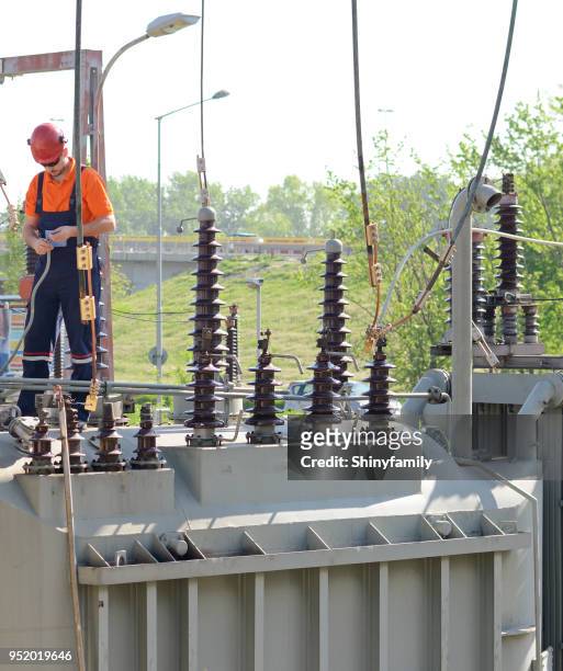 elektriker arbeiten auf hochspannung transformator im kraftwerk - sicherheitsausrüstung stock-fotos und bilder