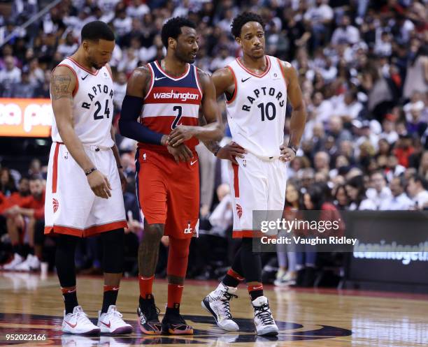 Norman Powell and DeMar DeRozan of the Toronto Raptors talk with John Wall of the Washington Wizards during the second half of Game Five in Round One...