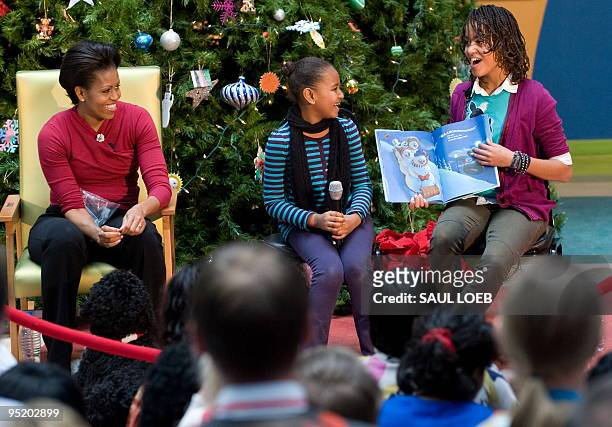 Malia Obama and Sasha Obama , daughters of US President Barack Obama, read the book "Snowmen at Night" by Caralyn Buehner, with their mother, First...