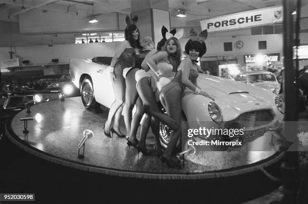 Bunny Girls drapped over an Aston Martin Volante car at the British International Motor Show in London 19th October 1965.
