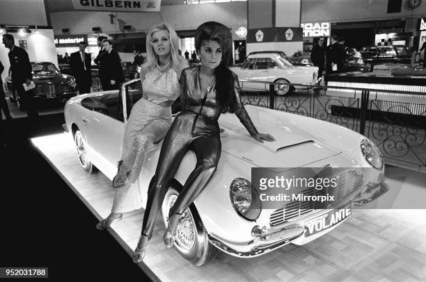 Models pose on the bonnet of a Aston Martin Volante at Motor Show 18th October 1966. The woman on the right is British actress, model and singer...