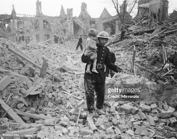 Fireman carries a young boy out of the rubble after a bombing raid, London, Circa 1940.