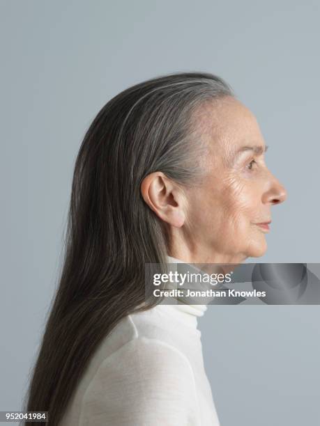 older caucasian female in profile against a gray background - profilo vista laterale foto e immagini stock