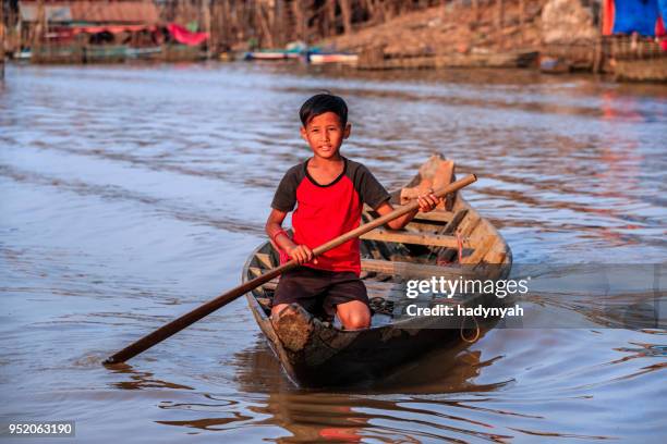 cambodian young boy rowing a boat, tonle sap, cambodia - boy river looking at camera stock pictures, royalty-free photos & images