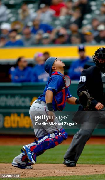 Juan Centeno of the Texas Rangers chases a pop-up during the game against the Oakland Athletics at the Oakland Alameda Coliseum on April 5, 2018 in...