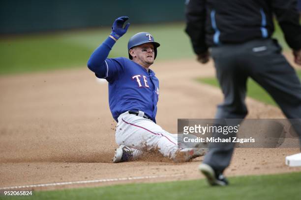 Ryan Rua of the Texas Rangers slides safely into third during the game against the Oakland Athletics at the Oakland Alameda Coliseum on April 5, 2018...