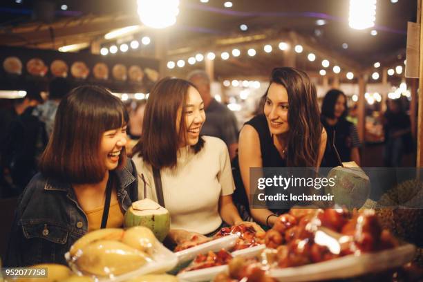 friends enjoying night time food markets in bangkok - night market stock pictures, royalty-free photos & images
