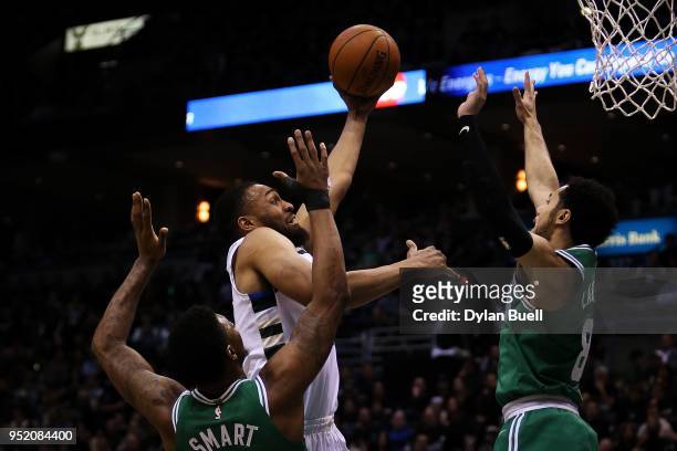 Jabari Parker of the Milwaukee Bucks attempts a shot while being guarded by Marcus Smart and Shane Larkin of the Boston Celtics in the fourth quarter...