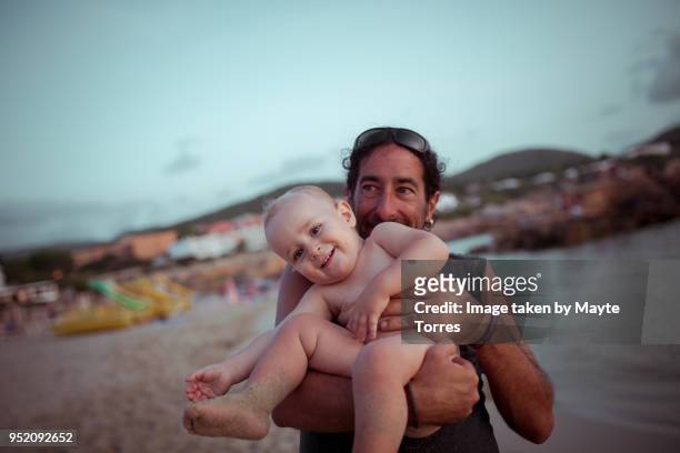 man holding his baby nephew in front of him at the beach - neefje stockfoto's en -beelden