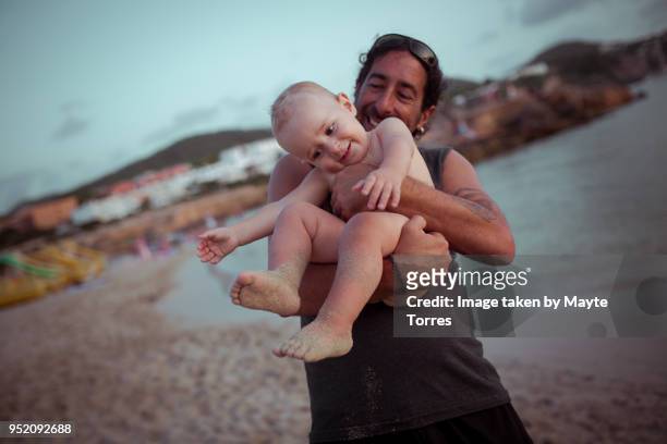 baby boy being held by his uncle at the beach - neefje stockfoto's en -beelden