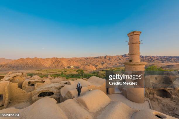 unknown tourist at the adobe, mud and brick ancient village of kharanaq, yazd province, iran - persische kultur stock-fotos und bilder