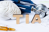TIA Acronym or abbreviation to medical concept or diagnosis of transient ischemic attack or small brain stroke. Word TIA stands among models of the brain, stethoscope and medicines in ampules or vials