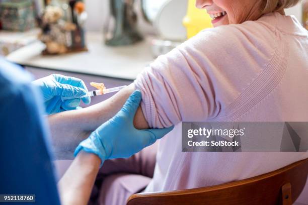 nurse injecting her patient in her home - amostra médica imagens e fotografias de stock