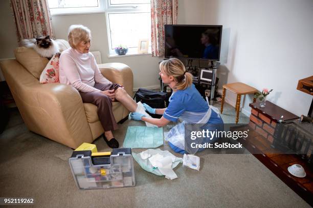 senior woman receives medical care at home - bandage stock pictures, royalty-free photos & images