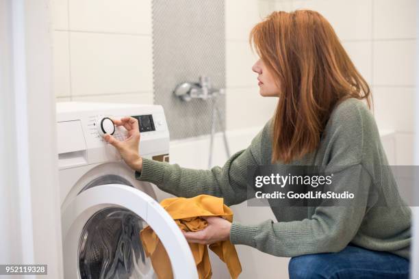 junge frau, die einstellung einer waschmaschine - washing machines stock-fotos und bilder