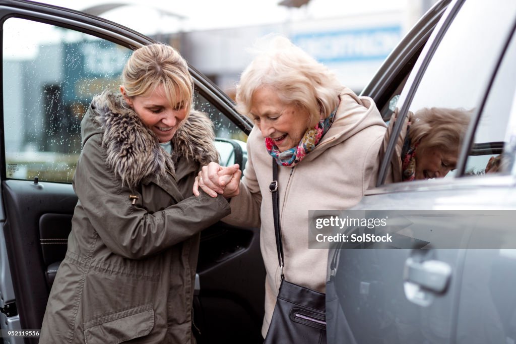 Eine ältere Frau aus dem Auto zu helfen