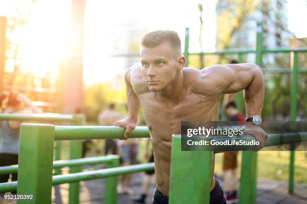 muscular man exercising in an outdoor gym - outdoor gym stock pictures, royalty-free photos & images