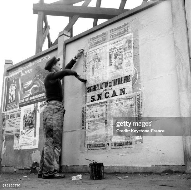 Homme collant des affiches de 'L'Humanité' au Havre, France, en 1955.