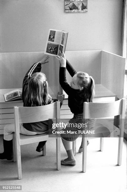 Petites filles lisant des livres dans une bibliothèque à Miramas, en 1983, dans les Bouches-du-Rhône, France.