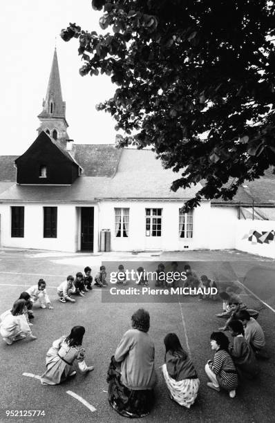 Enfants faisant la ronde dans la cour de récréation de leur école à Redon, en Ille-et-Vilaine, en 1988, France.