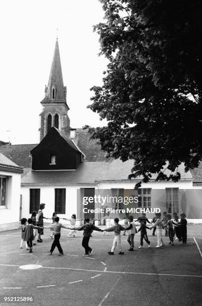 Enfants faisant la ronde dans la cour de récréation de leur école à Redon, en Ille-et-Vilaine, en 1988, France.