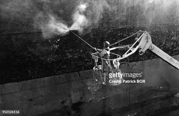 Ouvrier nettoyant la coque d'un bateau dans un chantier naval à Marseille, dans les Bouches-du-Rhônes, en 1986, France.