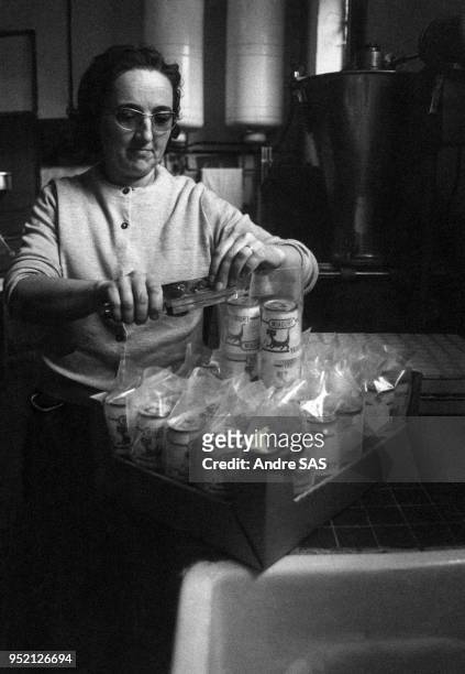 Employée emballant des pots de yaourt ?Miaourt? dans l'épicerie ?Les 5 Fermes? à Chamarande, en 1969, dans l'Essonne, France.