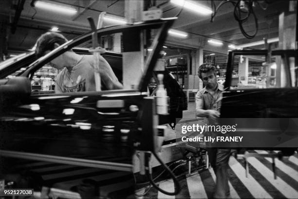 Ouvriers sur la chaine de production, mise en place des accessoires, usine Peugeot Talbot Poissy, France.