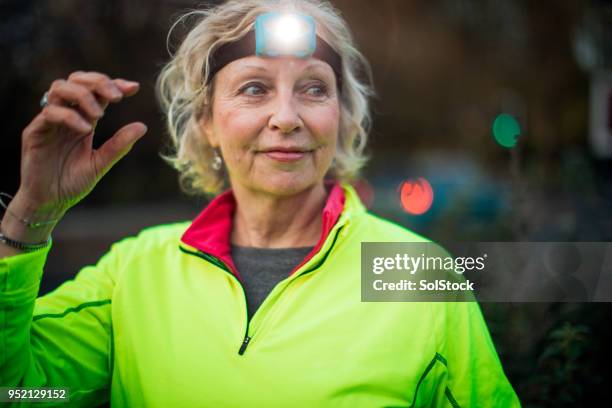 portrait of a senior female urban runner - head torches stock pictures, royalty-free photos & images