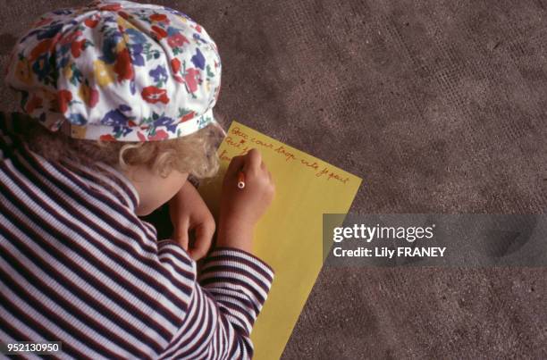 Petite fille écrivant une lettre lors d'une colonie de vacances du Comité Central d'Entreprise de la SNCF à Clairoix, en 2001, dans l'Oise, France.