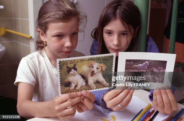 Petites filles lisant des cartes postales lors d'une colonie de vacances du Comité Central d'Entreprise de la SNCF à Clairoix, en 2001, dans l'Oise,...