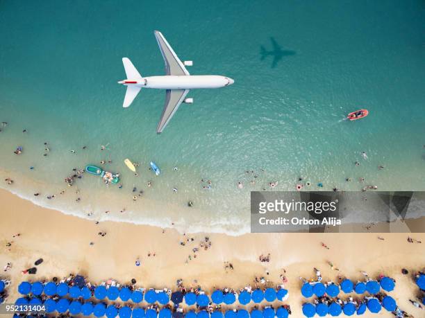 airplane flying over a crowded beach - beach plane stock pictures, royalty-free photos & images